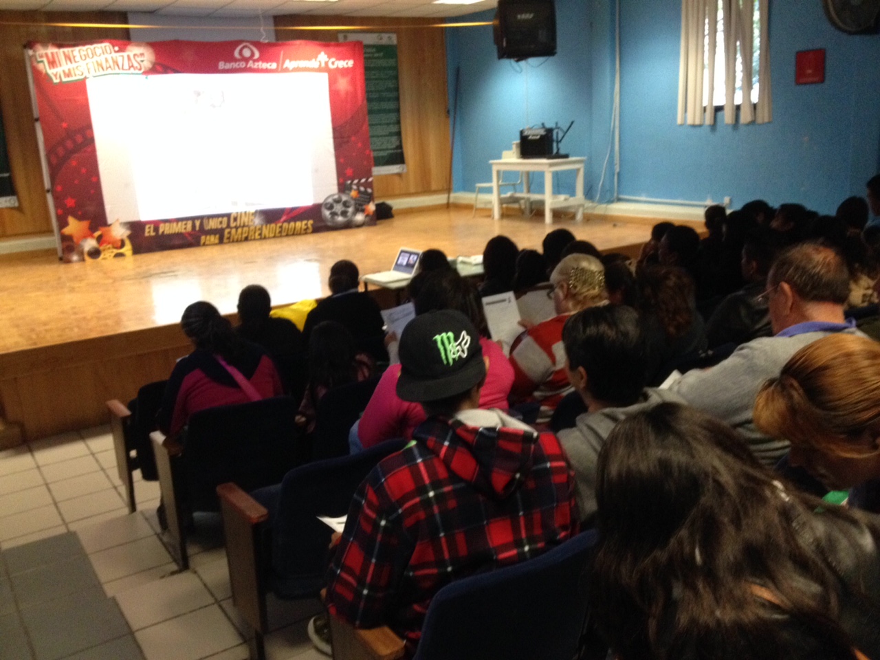 Vista del escenario y padres tomando el taller